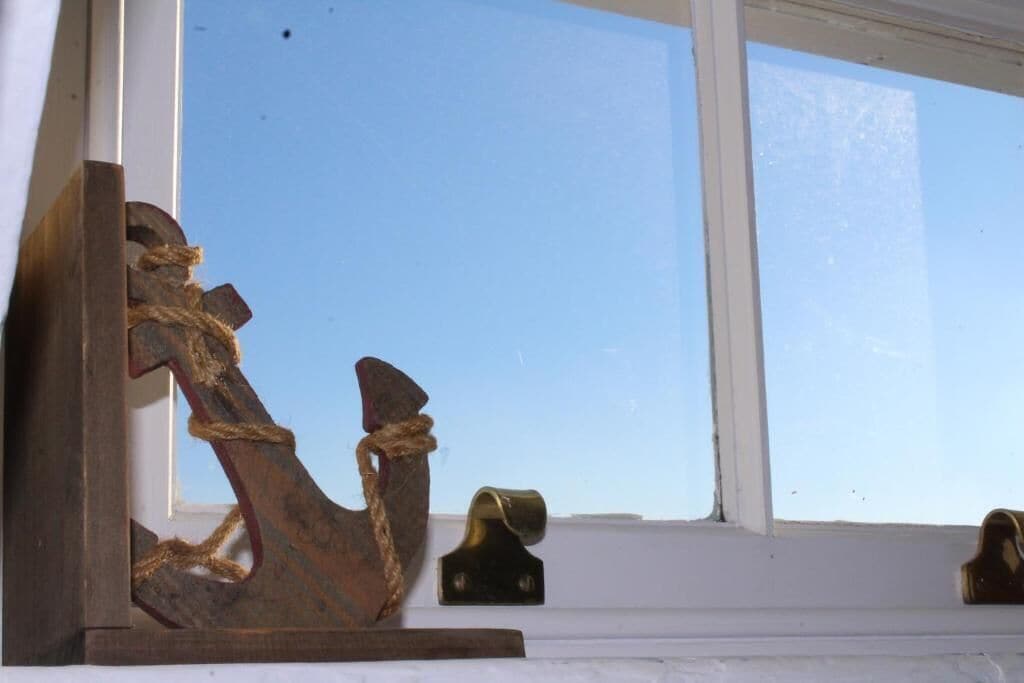 A wooden anchor sculpture on a window sill.