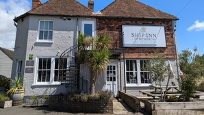 Un bâtiment à deux étages avec une enseigne indiquant : « Ship Inn – Pub de Dymchurch, restaurant, hébergement ».
