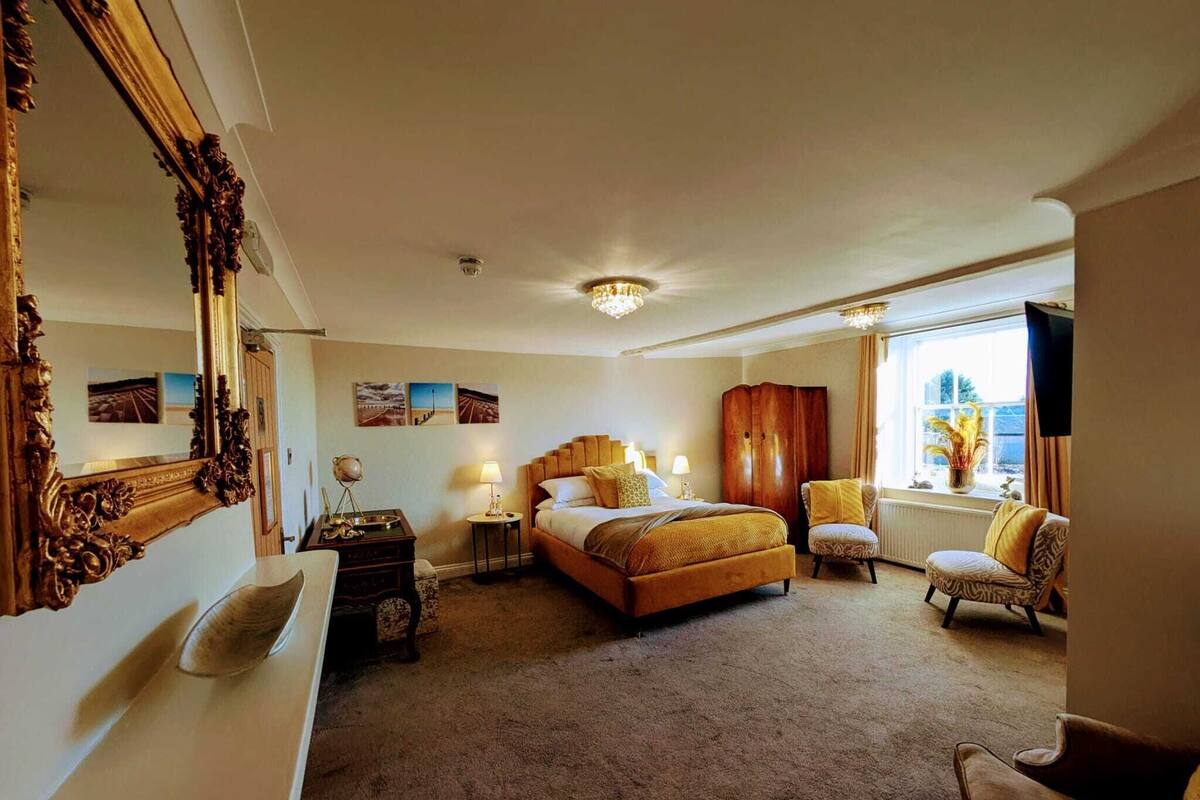 A hotel room with a large bed, a wardrobe, a desk, and a window with a view.