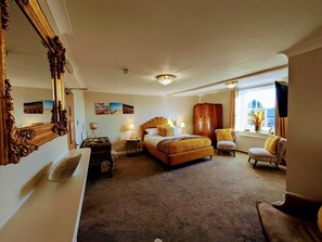 Habitación de hotel con una cama grande, un armario, un escritorio y ventana con vistas.