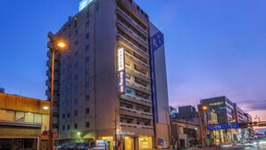 Ein mehrstöckiges Hotel mit auffälliger Beschilderung, einer Parkgarage und einer Straße mit Fahrzeugen.