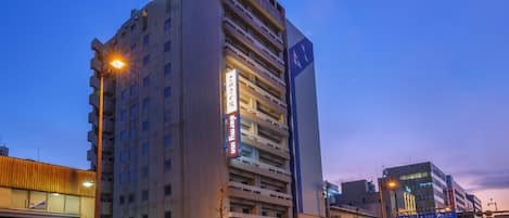 A multi-story hotel with a prominent sign, a parking garage, and a street with vehicles.