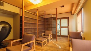 Ein Zimmer mit Massagesessel, Holzregal und Holzboden.
