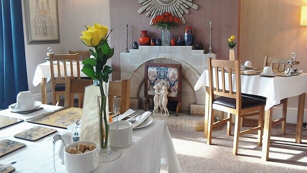 A dining area with a fireplace, a mirror, and a table set for two. - South Lodge (Bridlington)