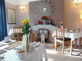 A dining area with a fireplace, a mirror, and a table set for two.