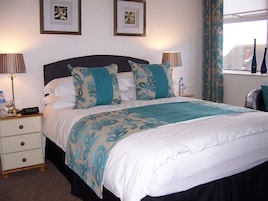 A neatly made bed with a floral-patterned bedspread, two bedside lamps, and a water bottle on the nightstand.