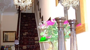 A staircase with patterned carpet, a chandelier, and decorative vases with flowers. - South Lodge (Bridlington)