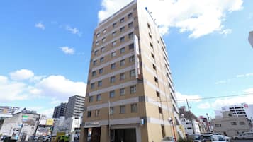 Um hotel de vários andares com design moderno, apresentando uma entrada imponente e uma área de estacionamento na frente.