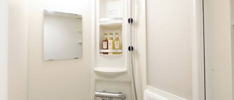 A bathroom with a white shower, a towel rack, and a shelf with toiletries.