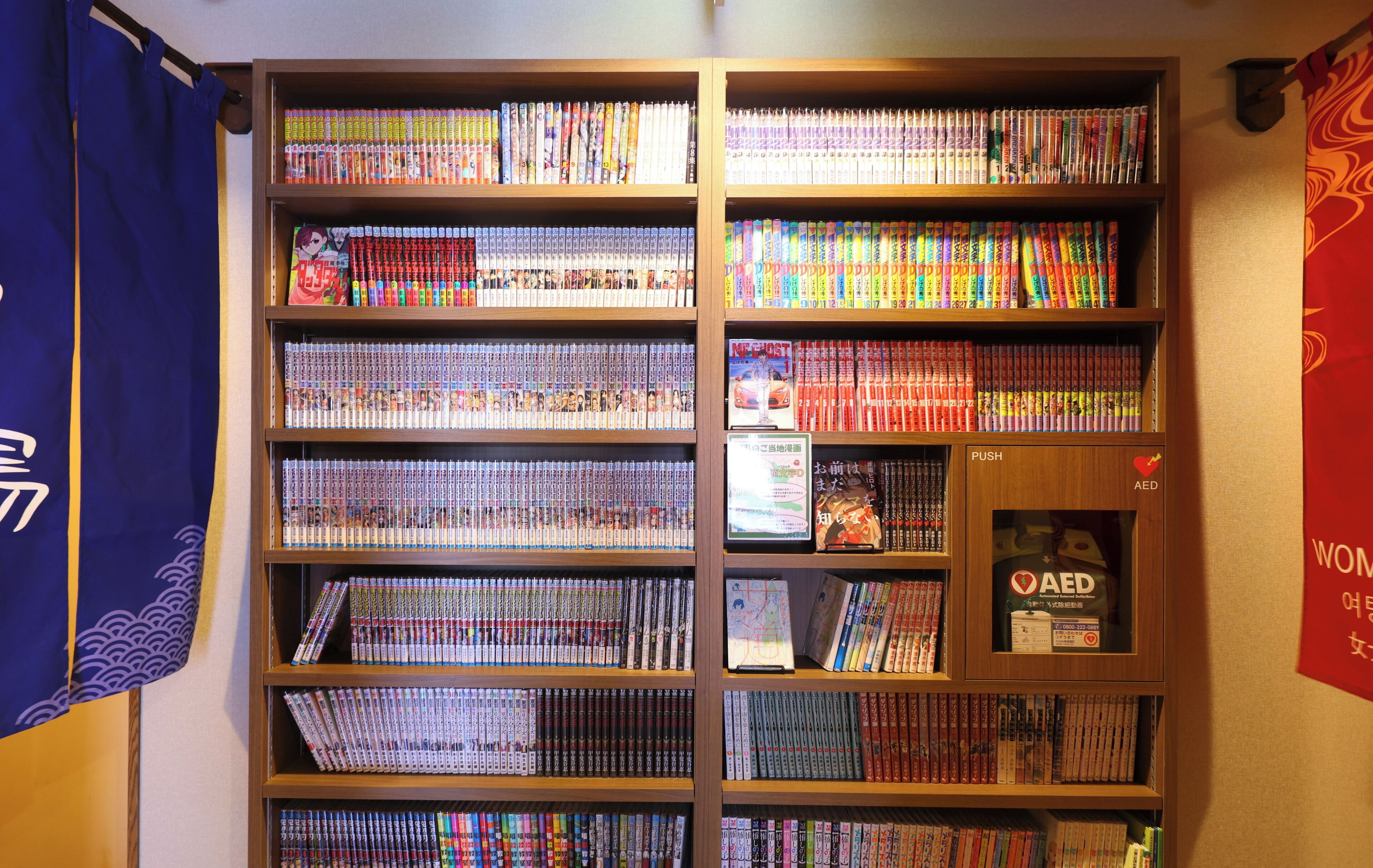 A bookshelf filled with books and magazines, a blue curtain, and a red banner with white text.