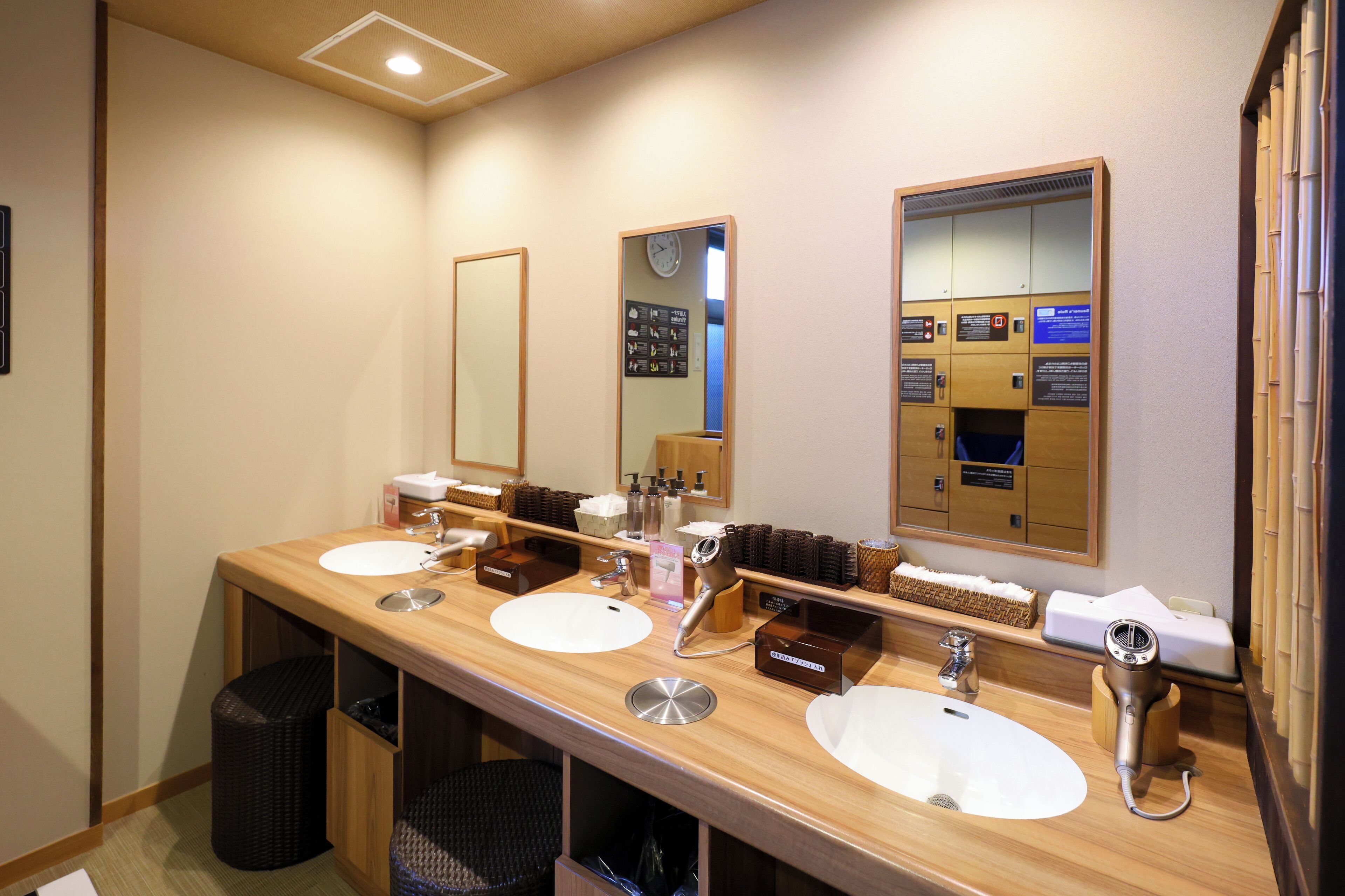 A hotel bathroom with three sinks, a mirror, and a hairdryer.