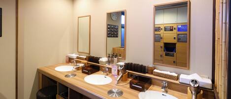 A hotel bathroom with three sinks, a mirror, and a hairdryer.