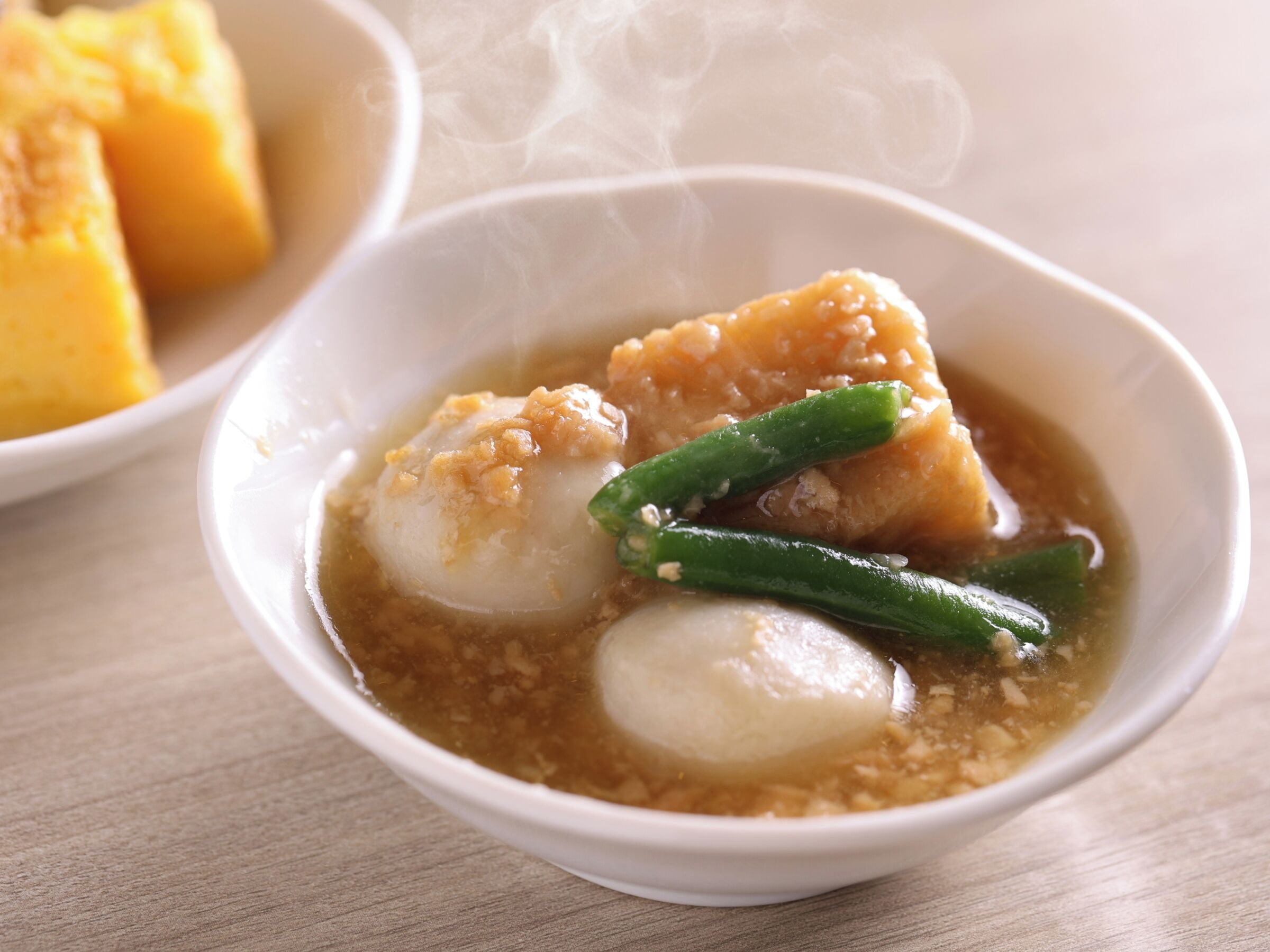 Un tazón de sopa con albóndigas y judías verdes.