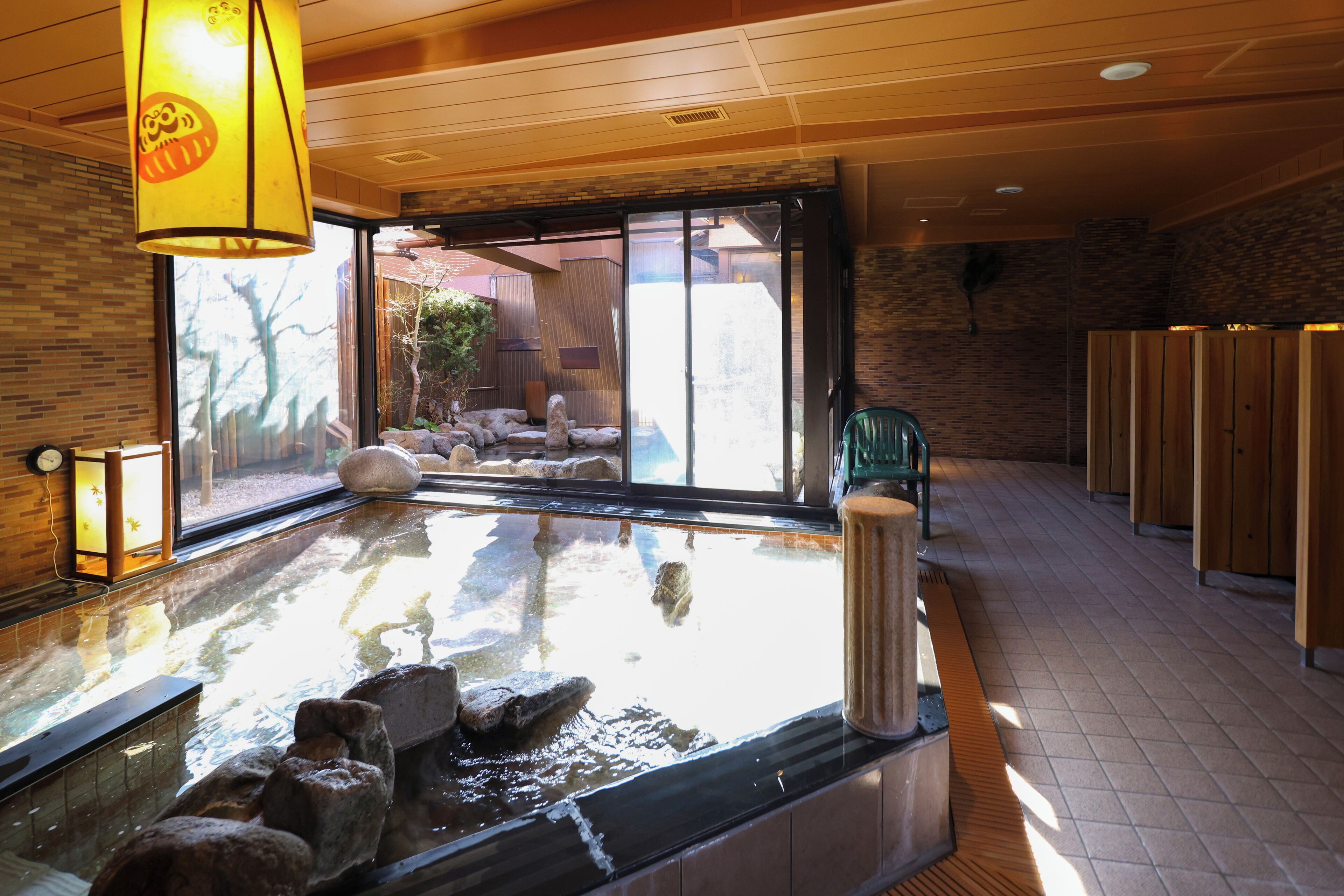 Zona de baño termal con suelo de madera, separador de vidrio y vistas al exterior.