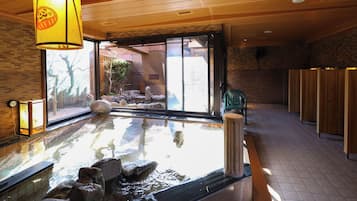 Zona de baño termal con suelo de madera, separador de vidrio y vistas al exterior.