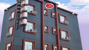 Un edificio de varios pisos con un diseño arquitectónico moderno, que cuenta con una serie de ventanas y unidades de aire acondicionado.