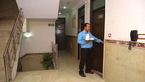 Pasillo de hotel con una escalera, señal de salida de incendios, una puerta con el número 203 y un teléfono en la pared.