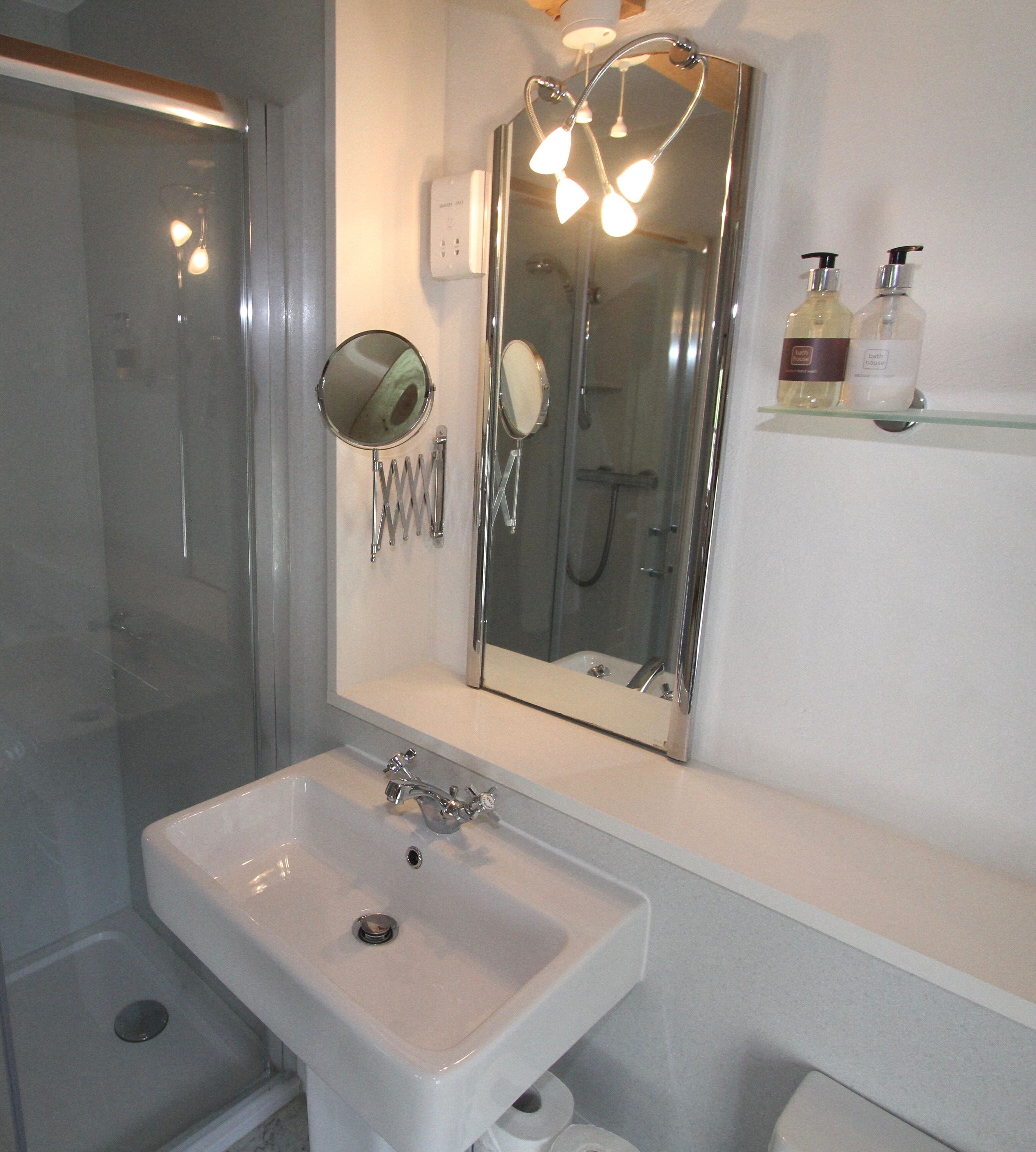 A bathroom with a sink, mirror, and shower.