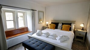 A hotel room with a bed, bedside tables, a bench, and a window. - Ashfield House (Skipton)