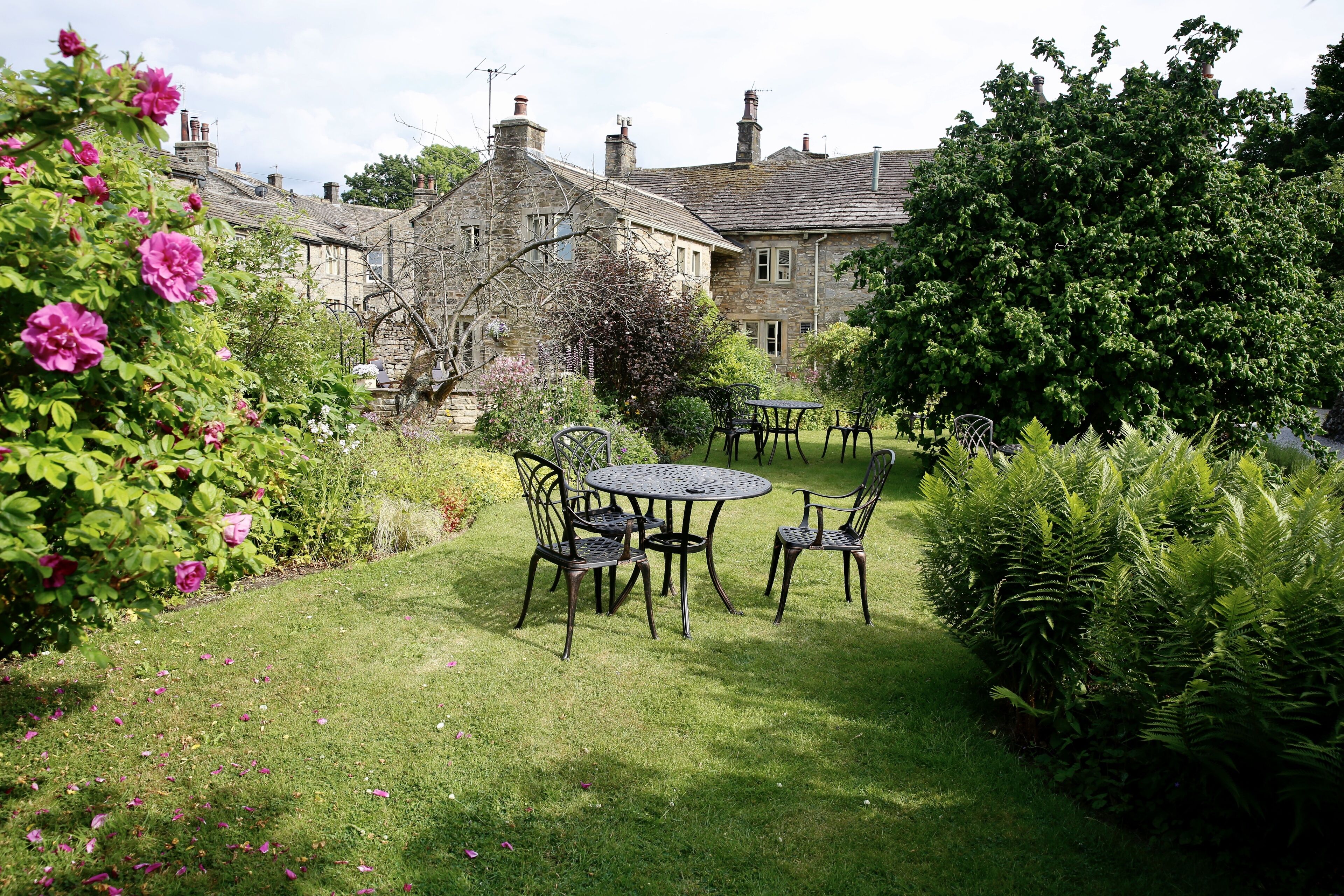 A stone building with a garden patio featuring a round table and chairs.
