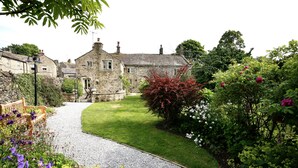 A stone building with a gravel path leading to a bench. - Ashfield House (Skipton)