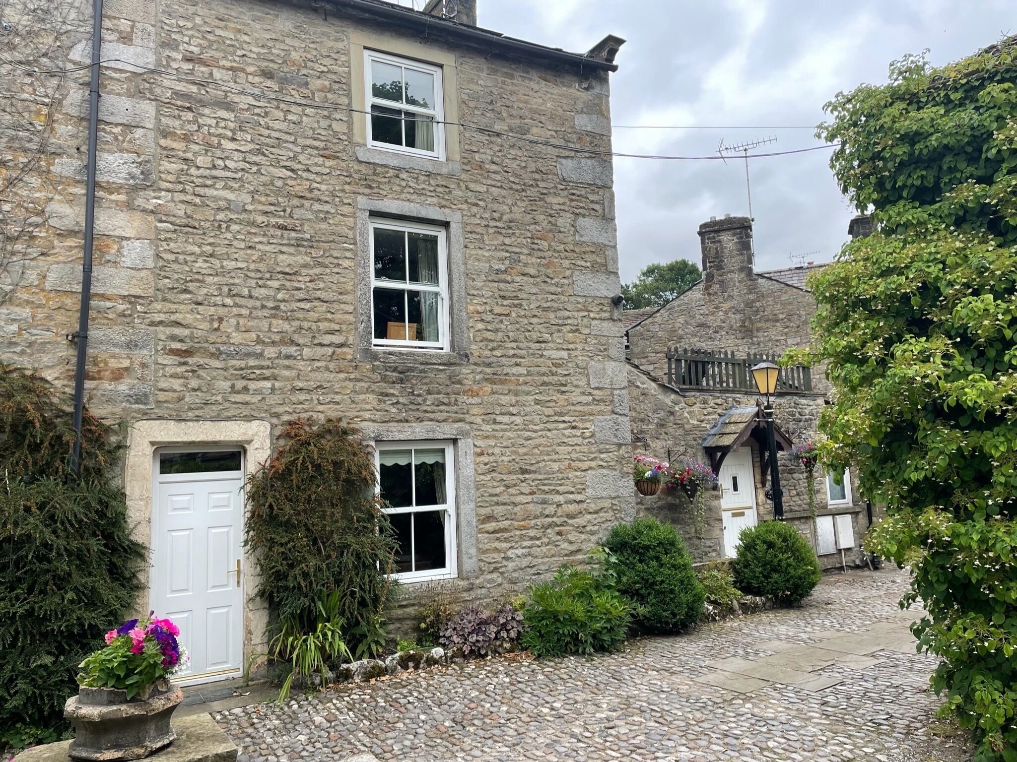 A stone building with multiple windows, a white door, and a cobblestone pathway.