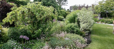 A well-maintained garden with various shrubs and flowering plants, a neatly trimmed lawn, and a stone pathway.