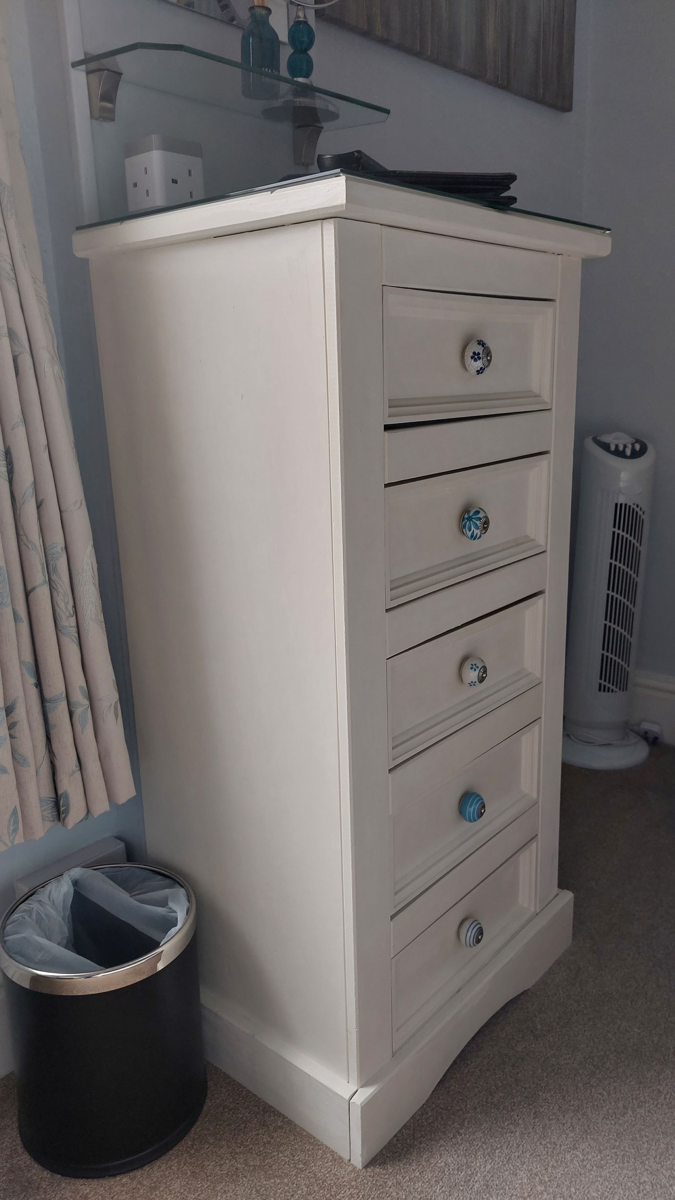 A white cabinet with drawers and a trash can.