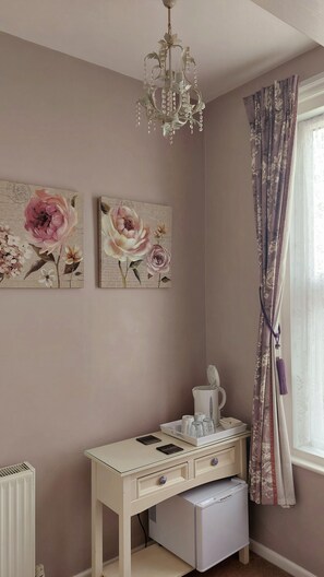 A room with a white desk, a radiator, a white appliance, and a window with curtains. - Two Beaches (Paignton)