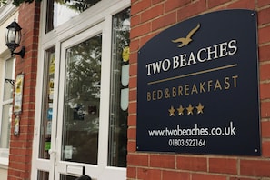 A black sign with gold lettering for 'TwoBeaches Bed & Breakfast' and a website address. - Two Beaches (Paignton)