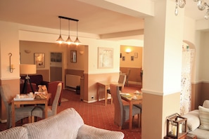 A hotel room with a dining area, a sofa, and a lamp.