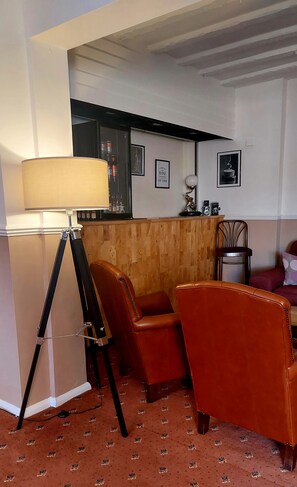 Um quarto com luminária de tripé, duas poltronas de couro, painel de parede em madeira e quadros emoldurados.