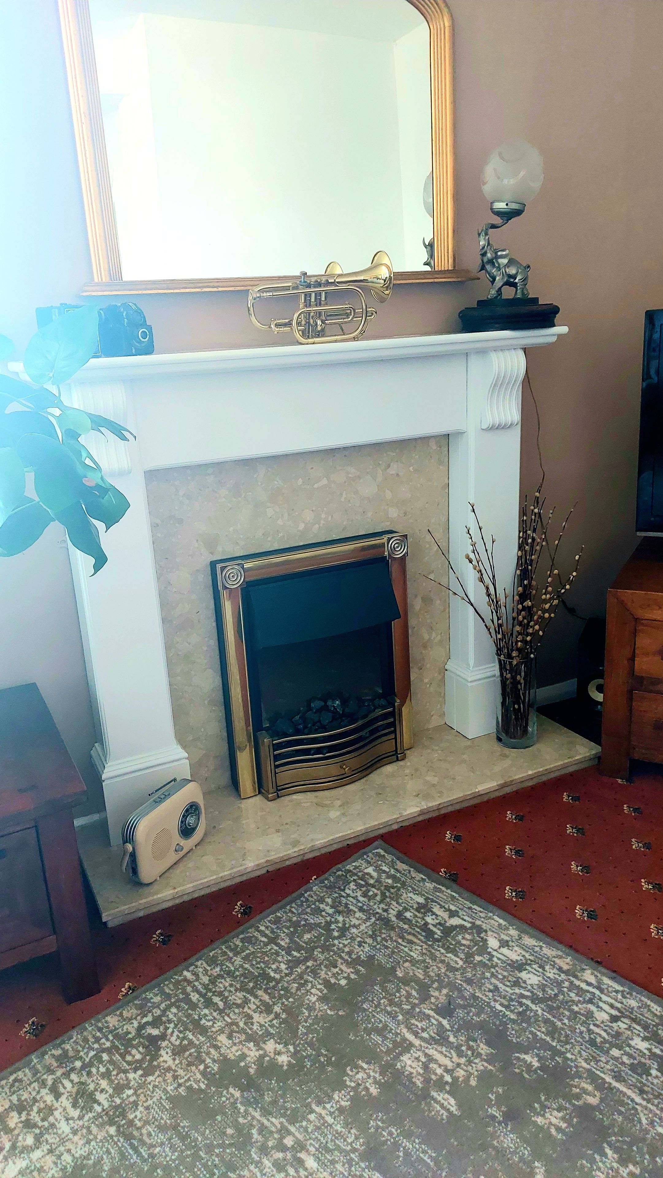 Una chimenea con repisa, un espejo encima y un accesorio de luz decorativo.