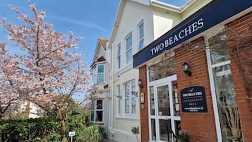 A two-story building with a sign reading 'TWO BEACHES BED & BREAKFAST'.