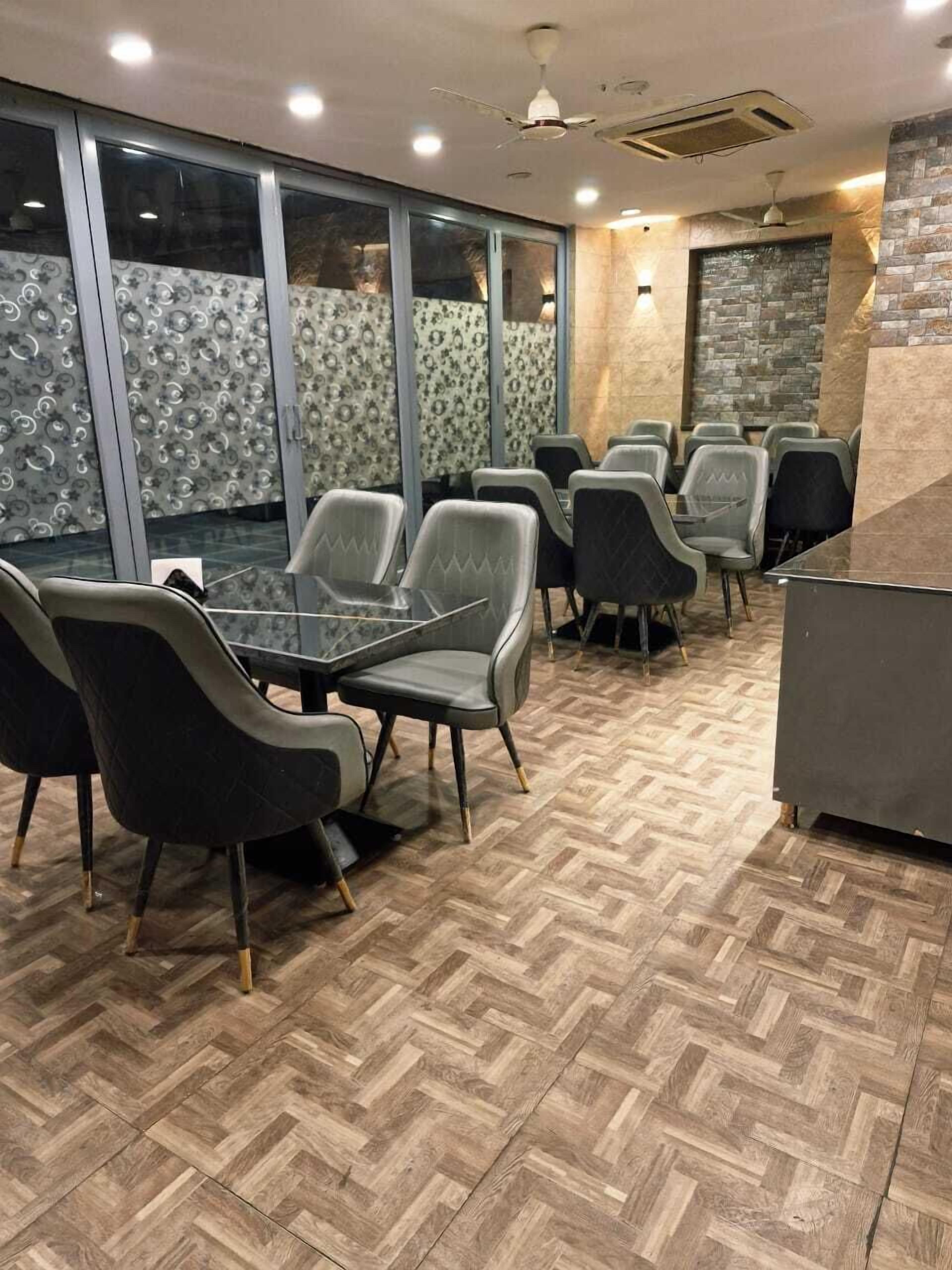 Un salón de conferencias con piso de madera estampada de espiga, sillas tapizadas en gris y una mesa de vidrio.