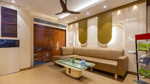 Una sala de estar moderna con una mesa de centro de vidrio, un sofá color beige y un ventilador de techo.