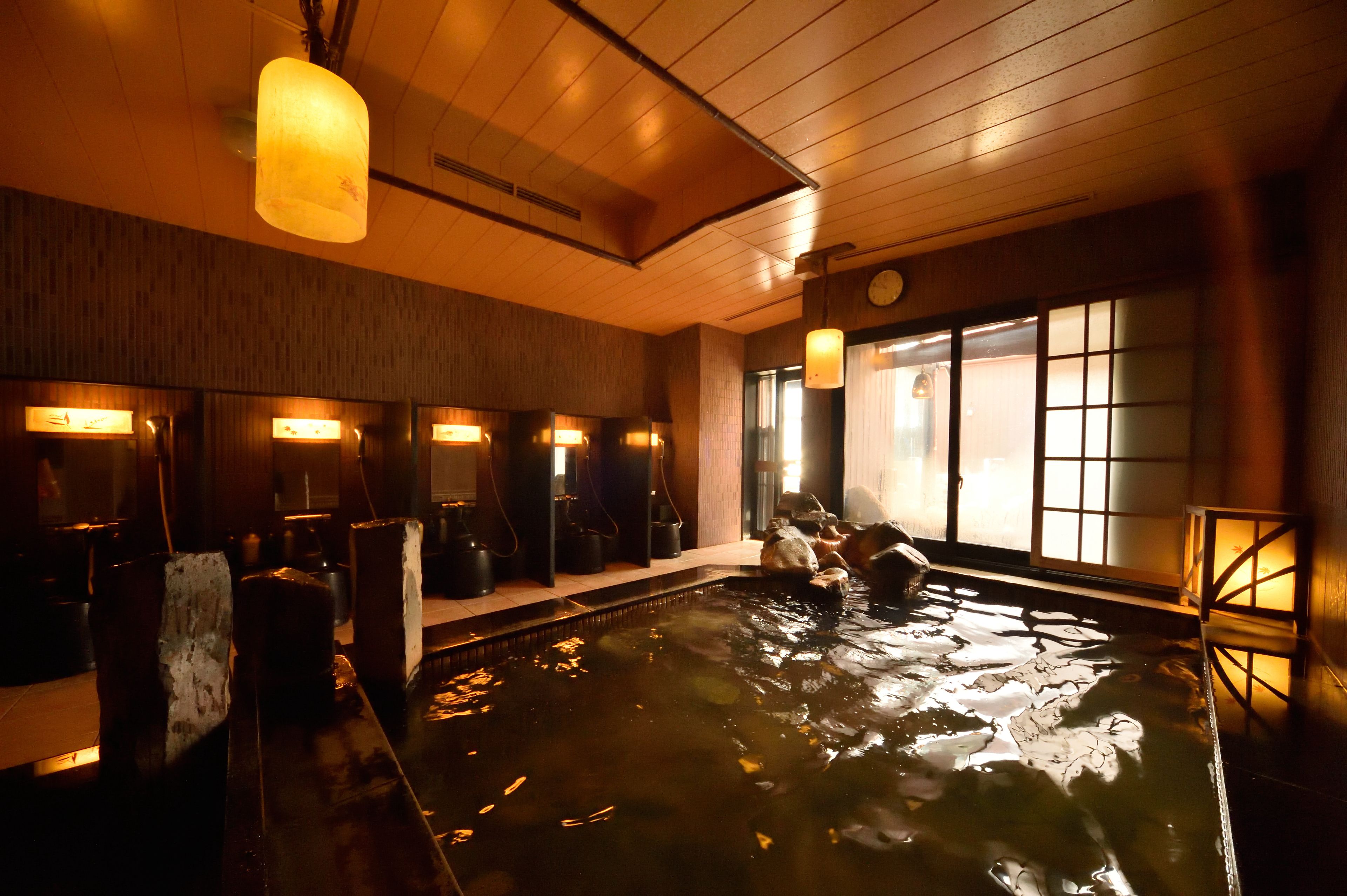 Een traditionele Japanse onsen met houten inrichting en een groot binnenzwembad.