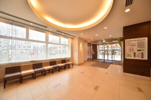 Un hall de hotel con mostrador de recepción, zona de estar y grandes ventanales.