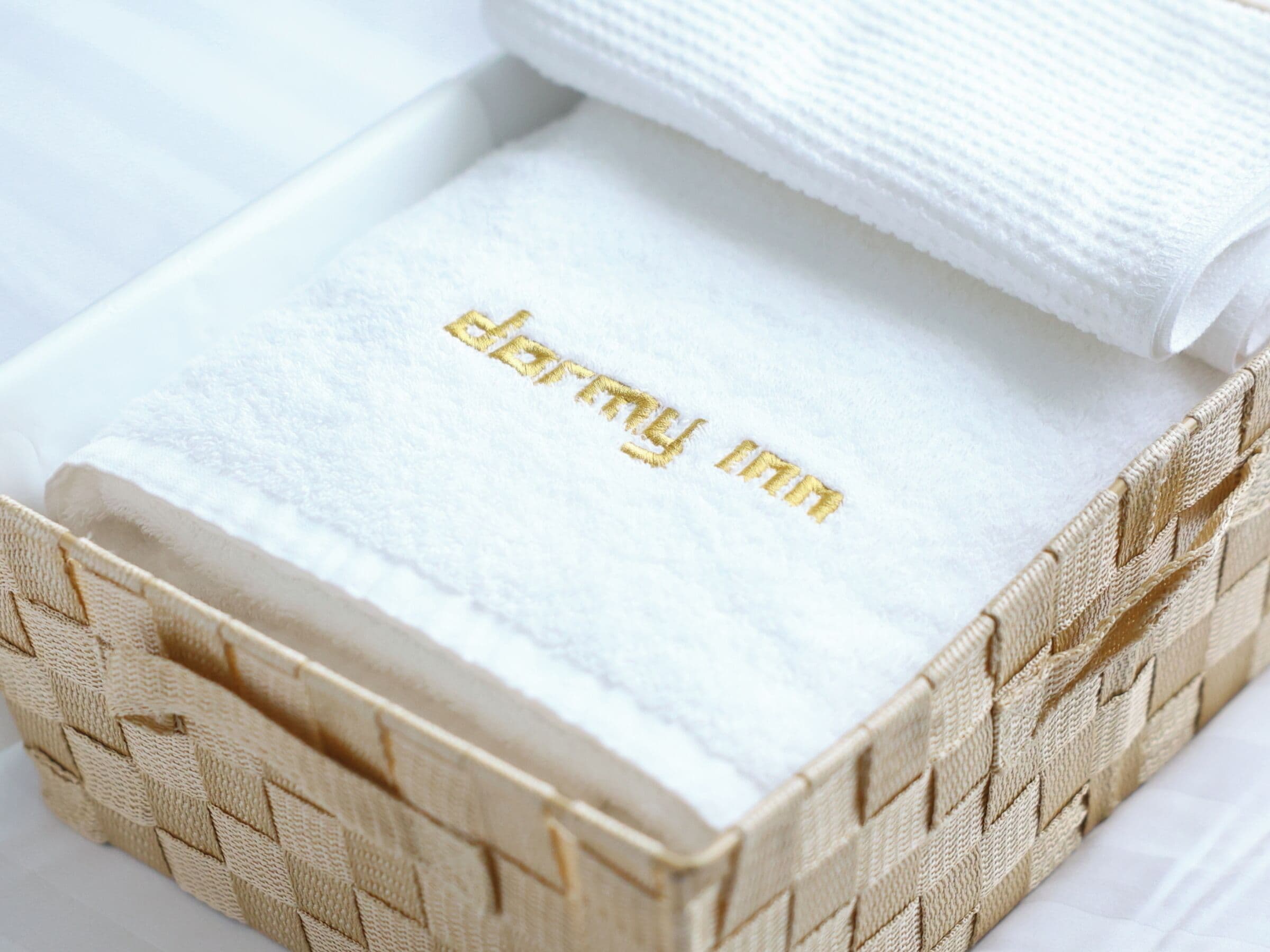 A white box with a woven texture and the text 'darby inn' embroidered in gold.
