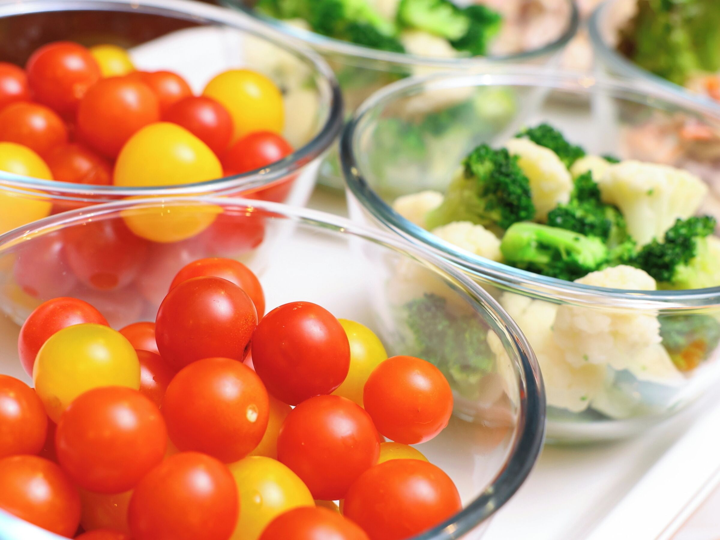 Une variété de légumes frais présentés dans des récipients en verre transparent.
