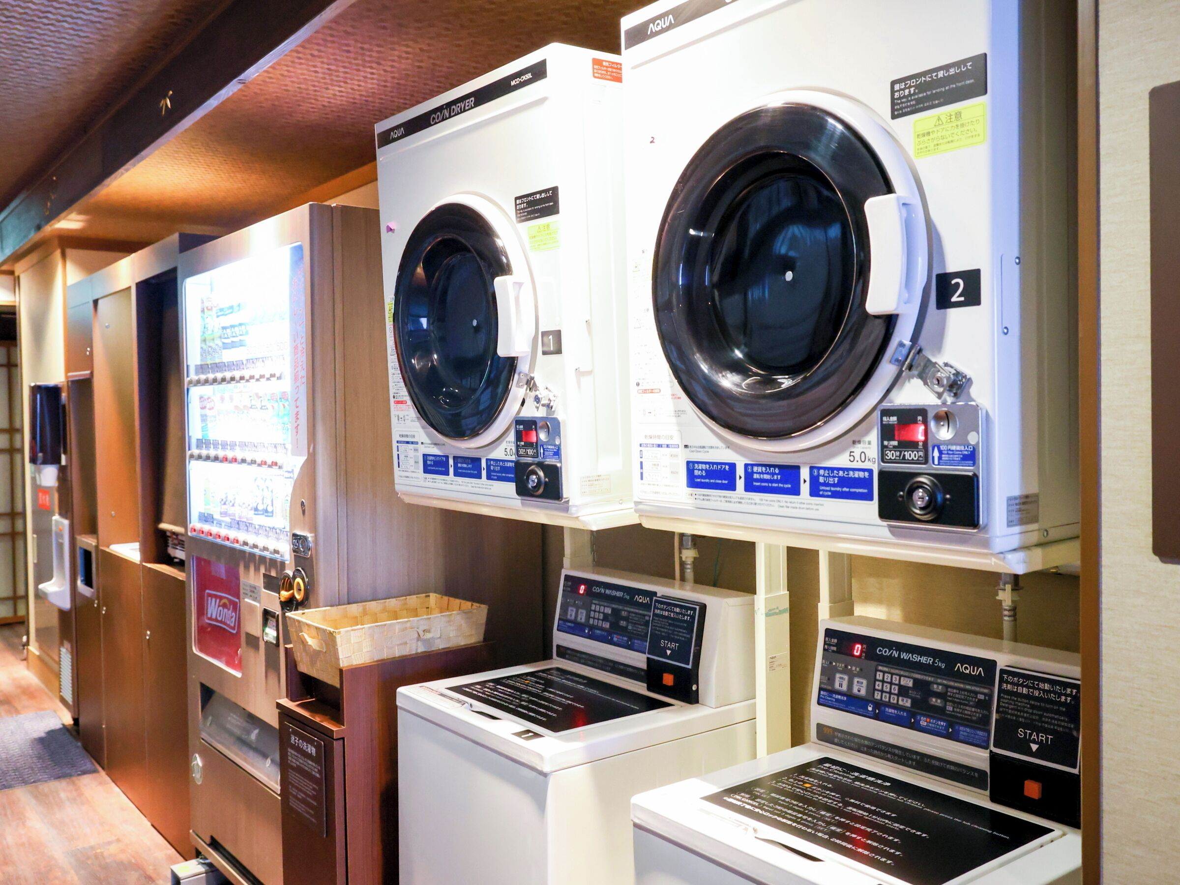 Une rangée de machines à laver et de séchoirs à pièces dans un établissement public.