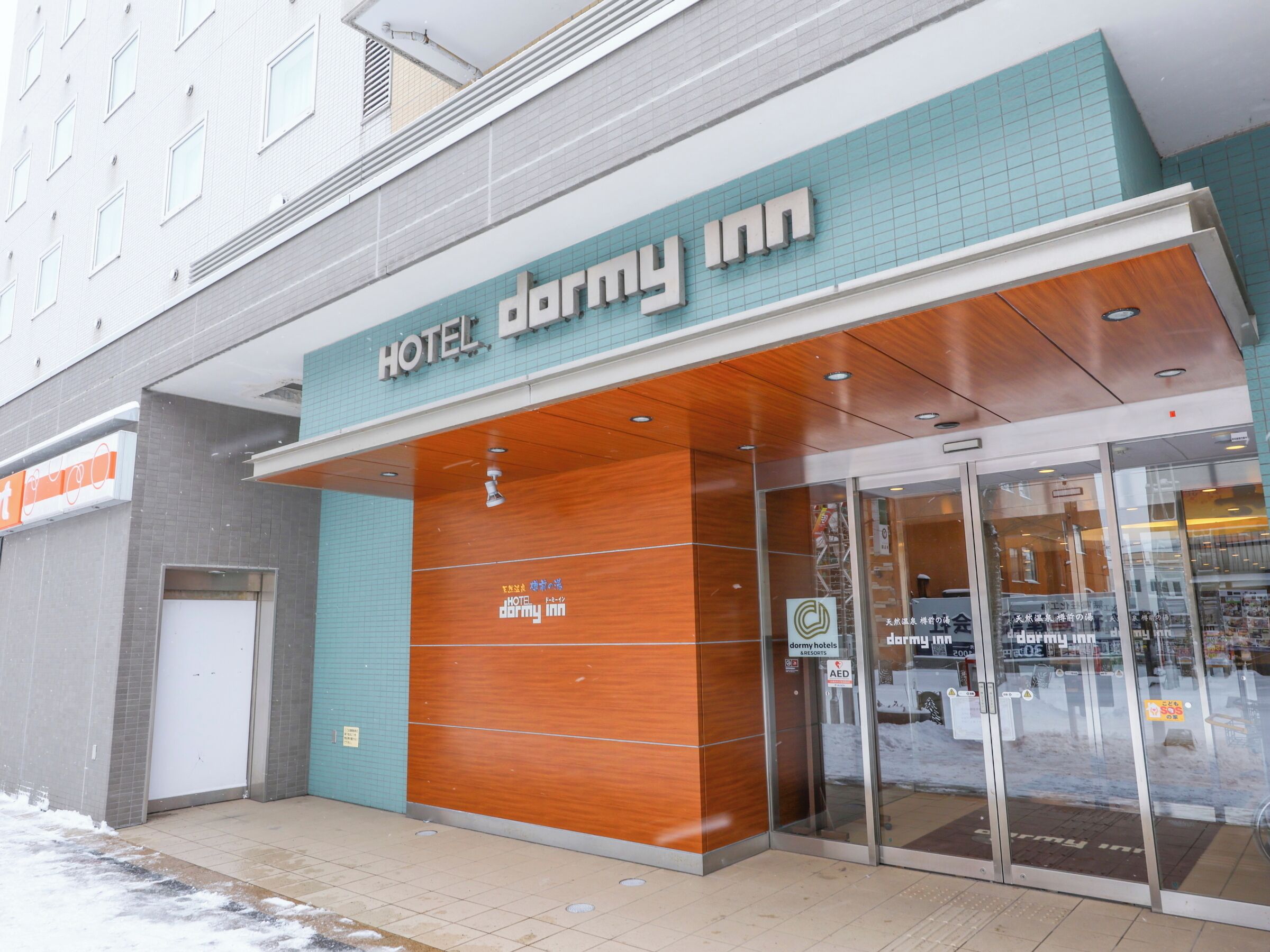 A hotel entrance with a sign reading 'HOTEL dormy inn.'
