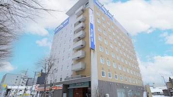A multi-story hotel with a prominent sign, a ground-level entrance, and a parking area.