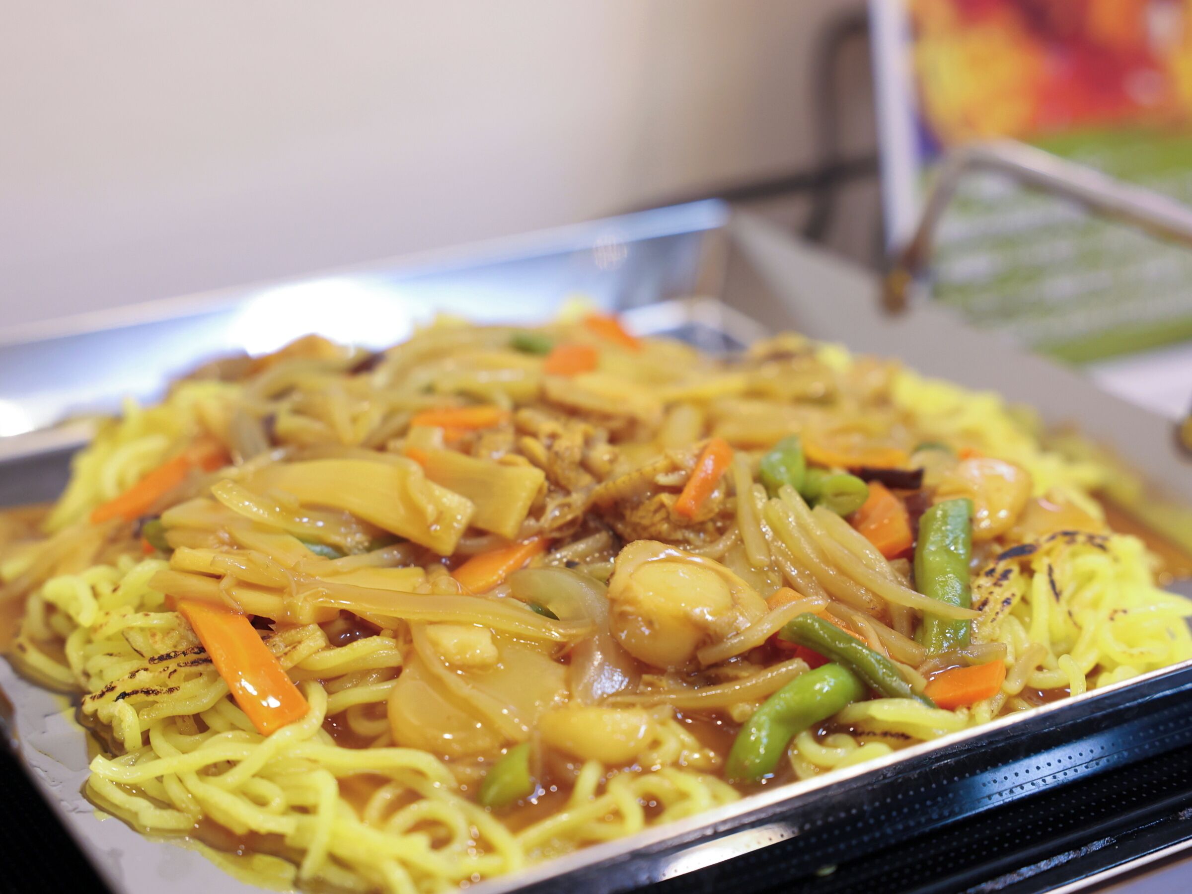 A tray of stir-fried noodles with vegetables and meat.
