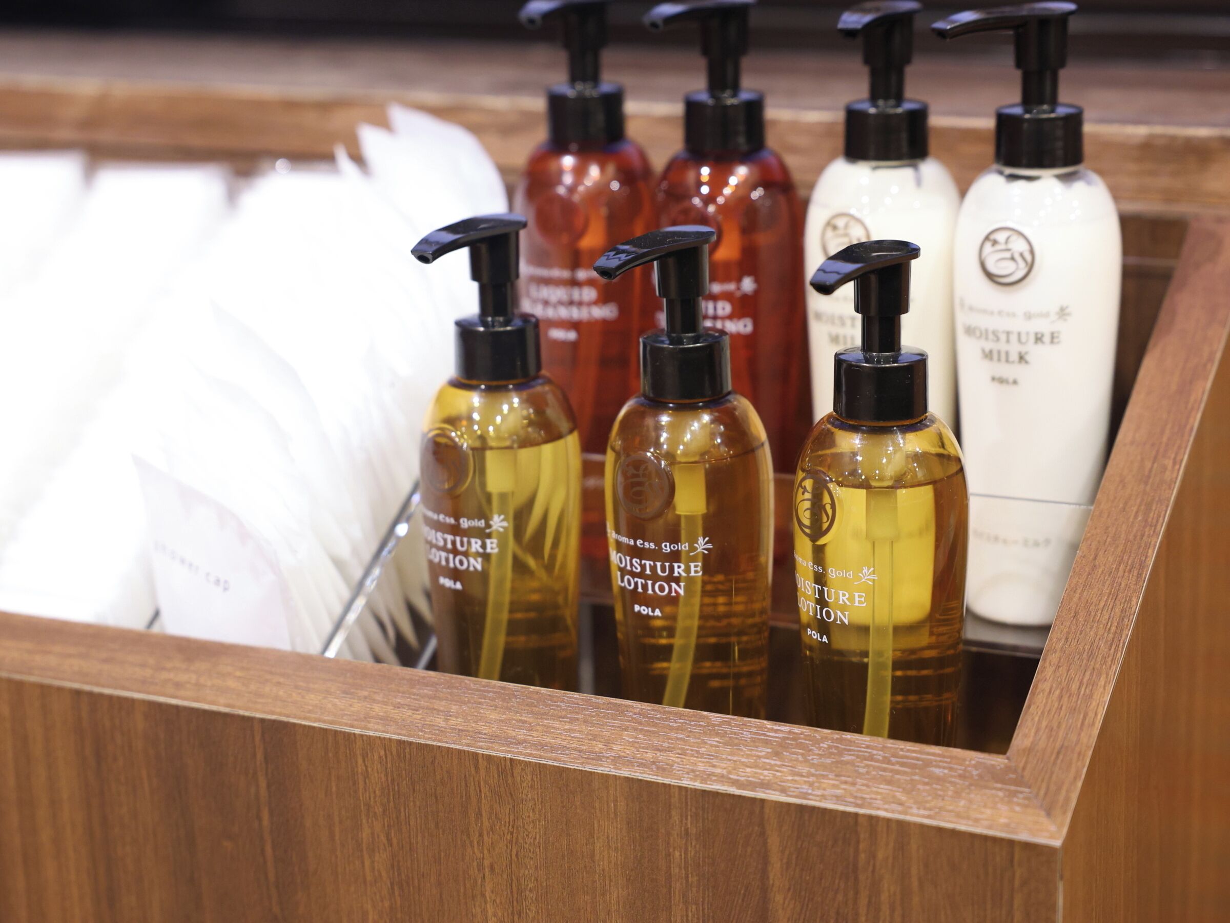 A wooden drawer containing various bottles of lotion and a white container.