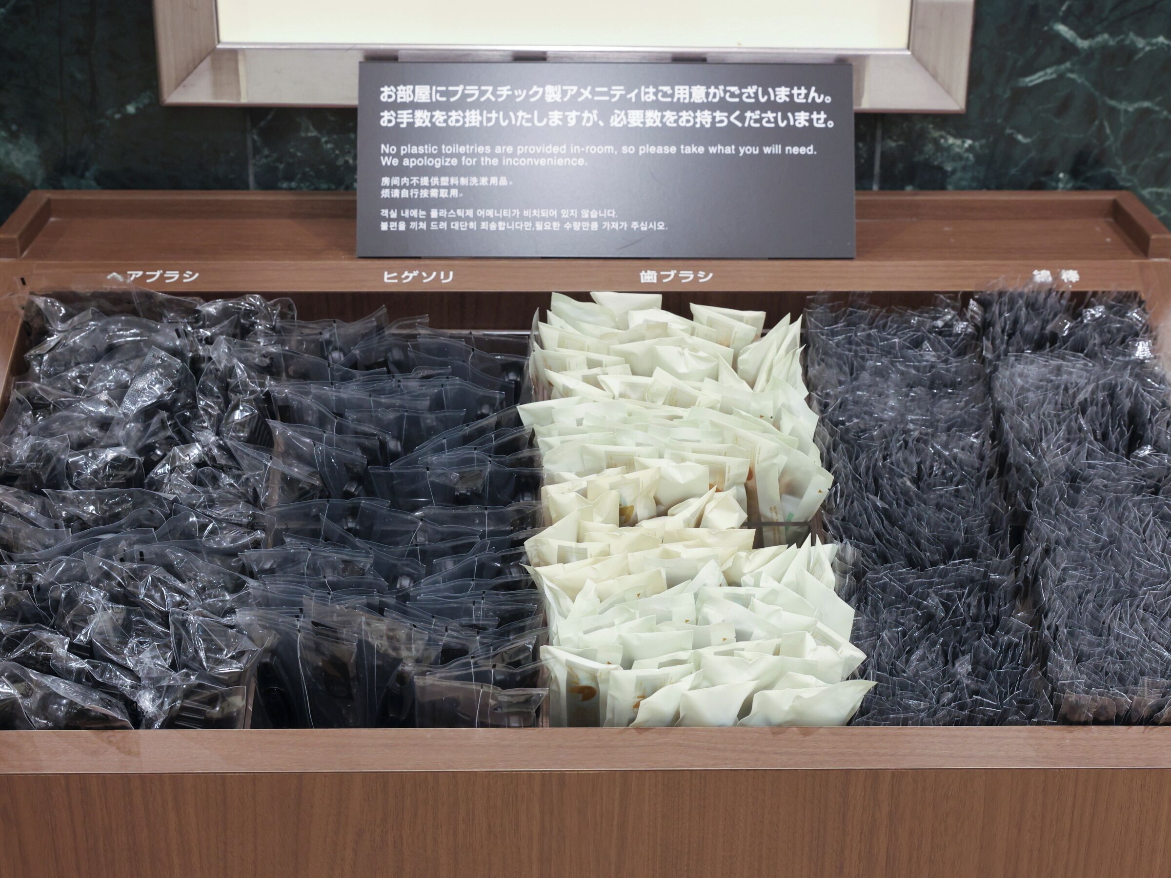 Un espace de rangement doté de compartiments étiquetés, contenant des sacs en plastique noirs et blancs, probablement destinés aux articles de toilette.