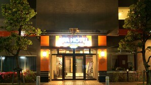 La entrada de un hotel con un letrero que dice "APA HOTEL" y una puerta de acceso visible.