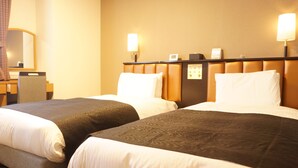 Habitación de hotel con dos camas, un escritorio, una silla y un panel de control en la pared.