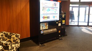 Máquina expendedora con pantalla digital, zona accesible para sillas de ruedas y puerta con un letrero.