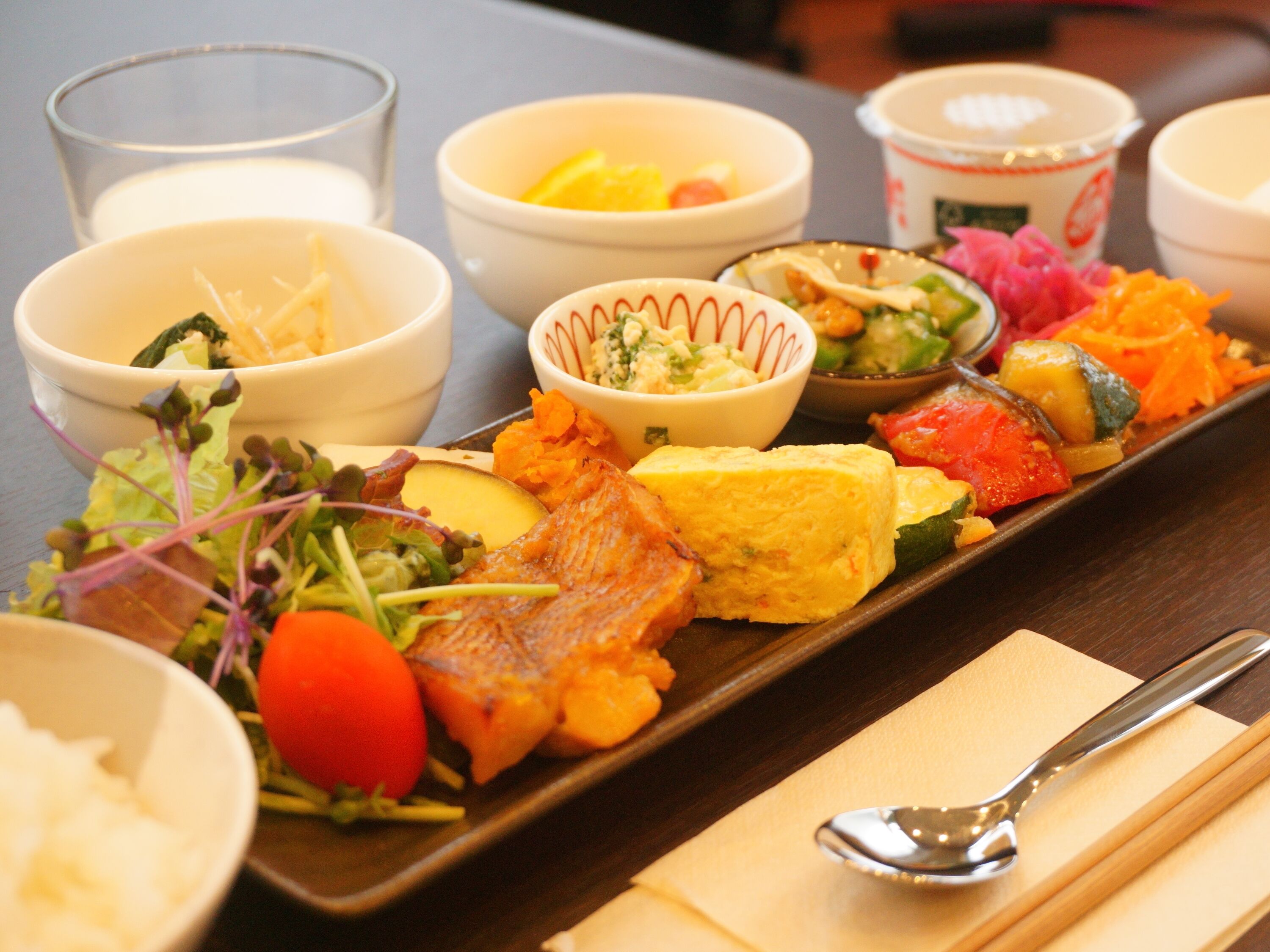 A variety of dishes on a tray, including vegetables, meat, and a piece of fish.